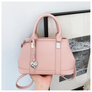 Detailed macro of pink litchi grain leather bag with heart charm and silver metal buckle