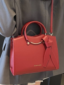 Red structured tote bag with gold ring handles and leather knot detail for women