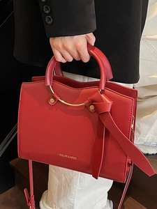Red large capacity tote bag with round metal handle and elegant leather bow detail