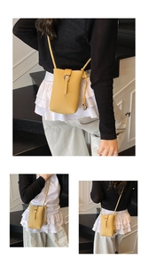 Détail du sac de téléphone en cuir jaune texturé avec boucle en métal argenté en U