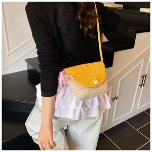 Detail of summer woven straw crossbody bag featuring yellow tones and a large pearl clasp