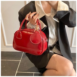 Détail du sac à main rouge en cuir verni avec surpiqûres et deux poignées
