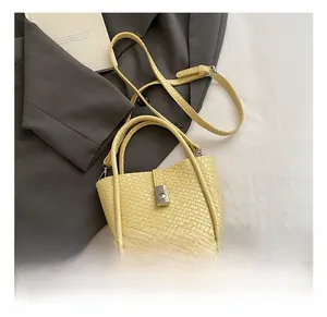 Detail of yellow woven bucket bag featuring a silver square lock and adjustable strap
