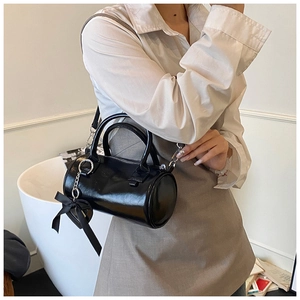 Detail of a black cylinder handbag with a ribbon bow and silver metal zipper