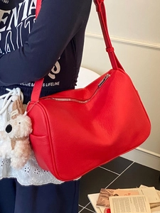 Minimalist red faux leather shoulder bag with a cute plush bear charm on a female model