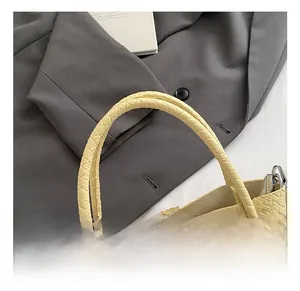 Close-up of yellow woven tote bag showing cylinder handle and silver metal hardware