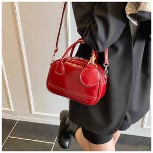 Détail du sac à main en cuir verni rouge avec surpiqûres blanches et nœud décoratif