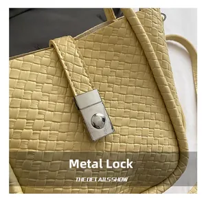 Detail of yellow woven bucket bag featuring a bright silver rectangular hardware buckle lock