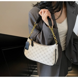Detail of off-white shoulder bag with grey geometric pattern and gold chain strap on model