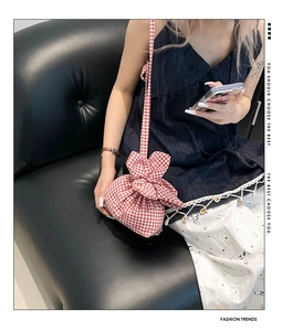 Détail du sac bandoulière à carreaux rouges avec nœud de serrage et fine lanière