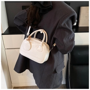 Sac Boston blanc brillant porté en bandoulière sur un blazer gris oversize, vue arrière