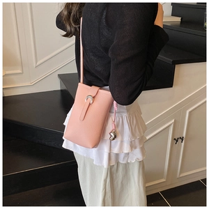 Détail du sac de téléphone en cuir rose avec texture litchi et pendentif coeur