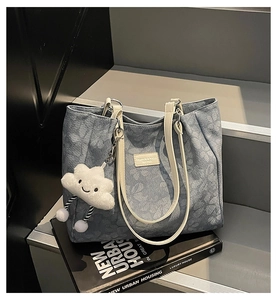 Detail of light blue floral embossed tote bag with white leather straps and cloud charm