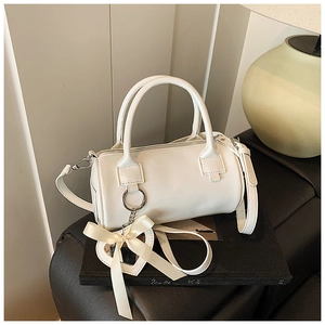 Detail view of white cylinder bag with a heart mirror charm and detachable shoulder strap