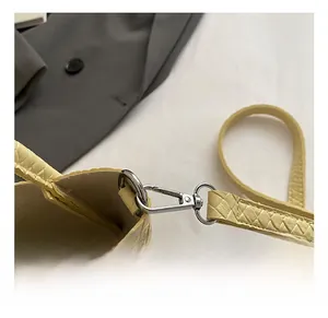 Detail shot of the pale yellow woven bag showing the silver metal hook and strap texture