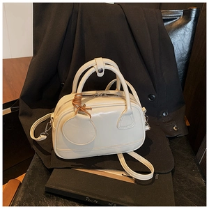 Détail du mini sac bowling blanc crème avec fermeture éclair et nœud sur costume noir