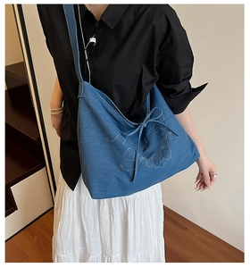 Detailed shot of large denim tote bag featuring side bow and sparkly rhinestone text
