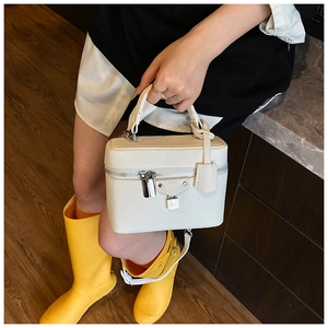 Close-up of white lychee pattern handbag with silver H-logo lock and dual zippers