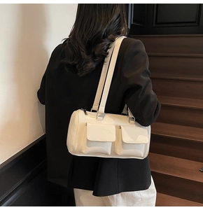 Detail view of cream white underarm bag with double front pockets and silver buckles