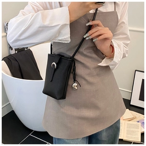 Détail d'un petit sac à téléphone en cuir grainé noir avec fermoir argenté porté