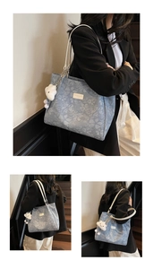 Detail view of light blue floral tote bag with white leather straps and cloud plush charm
