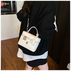 Detail of white mini vanity bag with litchi texture and silver padlock on a model