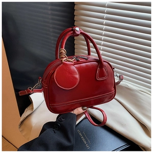 Détail du sac Boston en cuir rouge avec coutures blanches et finitions métalliques vintage