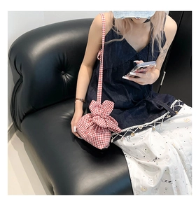 Détail du sac bandoulière à carreaux rouges avec cordon de serrage et nœud déco