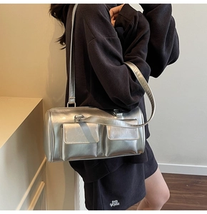 Side view of silver metallic Boston bag with two flap pockets on model's shoulder