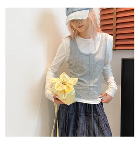 Détail d'un sac à main en soie jaune en forme de fleur porté avec une jupe à carreaux