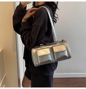 Detailed view of a silver metallic shoulder bag with two functional buckle pockets and strap