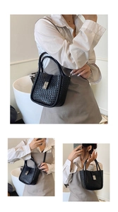 Detail of black woven bucket bag showing silver lock and adjustable shoulder strap