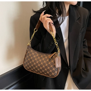 Detail of vintage baguette bag featuring geometric patterns and metal chain strap