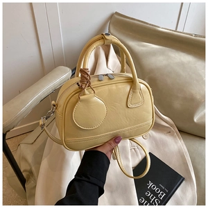 Gros plan sur un sac bowling crème au grain de cuir fin avec pendentif rond