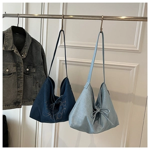 Detail showing deep and light blue denim tote bags with rhinestone letters and bow details