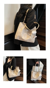 Detail of beige jacquard tote bag featuring a floral texture and plush cloud charm