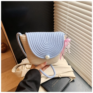 Detail of woven straw crossbody bag with light blue flap, pearl buckle and bow decoration