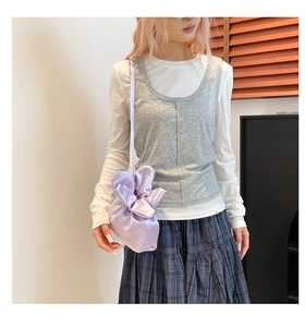 Détail du sac bandoulière en satin lilas avec un nœud floral 3D et une finition en soie