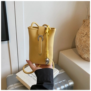 Détail du mini sac à portable jaune en cuir grainé avec boucle fer à cheval et pendentif cœur