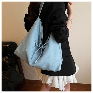 Detail of light blue denim tote bag with lucky rhinestone letters and bow tie side detail