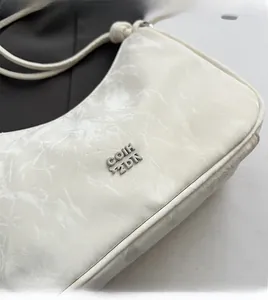 Close-up of white marble pattern shoulder bag featuring silver metal logo detail