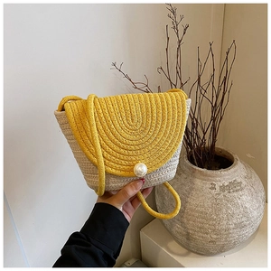 Detail of hand-woven straw crossbody bag with large pearl button and yellow flap