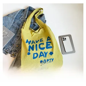 Détail du sac cabas en toile jaune à texture gaufrette avec imprimé bleu graphique