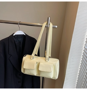 Detail of a creamy yellow patent leather Boston bag featuring two buckled front pockets