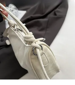 Close-up of cream white PU shoulder bag featuring silver ring hardware and knotted strap detail