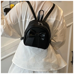 Close-up of a black mini PU leather backpack with a large signature bow and silver zipper