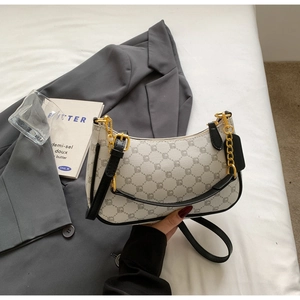 Detail of beige crescent bag with geometric pattern, black leather strap and gold chain