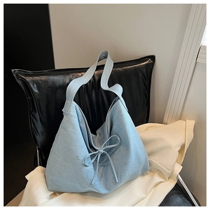 Detailed view of denim tote bag with rhinestone lettering and stylish bow tie decoration