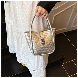 Close-up of a silver woven bucket bag with metal buckle and dual top handles