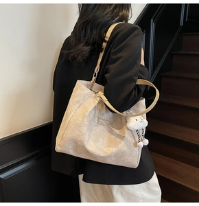 Detail of beige jacquard tote bag with leather straps and cute cloud charm on shoulder